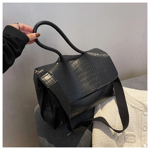 Detailed macro view of black crocodile pattern texture and handle on commuter tote bag