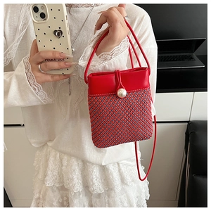 Detail of a red woven mini crossbody bag featuring a pearl button and mixed texture design