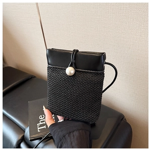 Detail of black woven straw phone bag featuring large pearl button and leather trim
