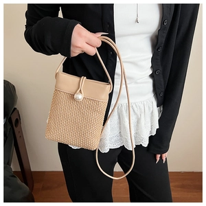 Close-up of woven straw mini bag with pearl detail and faux leather flap on model