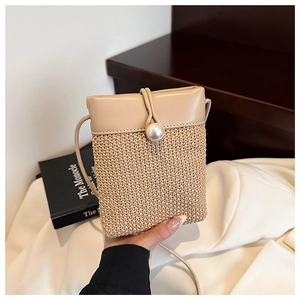 Detail view of woven straw crossbody bag with leather trim and faux pearl closure
