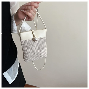 Detail of mini straw crossbody bag with faux pearl closure and cream leather stitching
