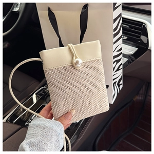 Close-up of woven straw mini bag with cream leather flap and pearl button detail