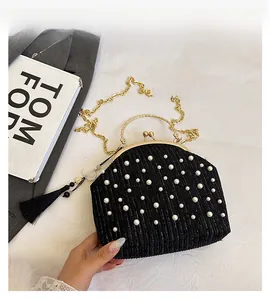 Détail du sac de soirée plissé noir avec perles, anse dorée et breloque fleur de camélia