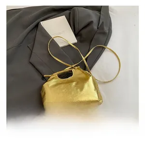 Macro shot of metallic gold glossy shoulder bag with sleek strap on grey fabric