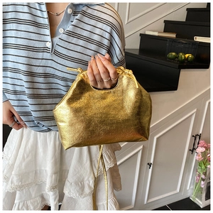Detail of metallic gold textured handbag with pleated design and golden zipper strap