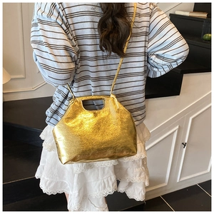 Detailed view of glossy gold metallic handbag with sleek cutout handle and shoulder strap