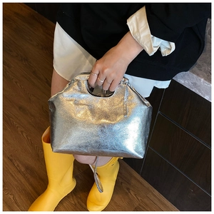 Silver metallic cloud handbag featuring textured finish and top cutout handle detail