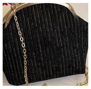 Détail du tissu noir plissé scintillant et fermoir vintage doré avec bandoulière chaîne
