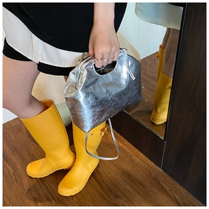 Detail of silver metallic pleated cloud bag featuring glossy faux leather and slender strap