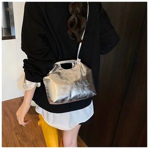 Detail of silver metallic textured crossbody bag with top handle and glossy finish