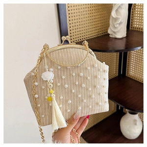 Détail du sac de soirée plissé champagne avec perles, cadre en métal et élégant pompon