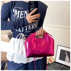 Close-up of metallic rose pink handbag featuring a hollow handle and glossy finish