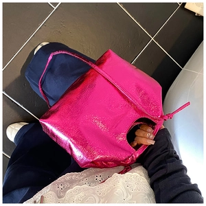 Detail of glossy fuchsia crossbody bag with round handle and knot accents