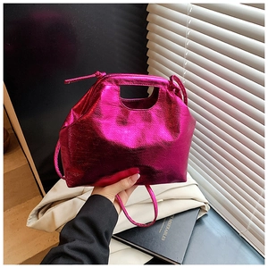 Detail of metallic rose red handbag featuring a cutout handle and textured finish