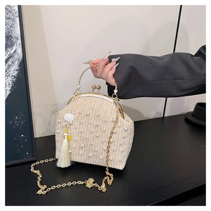 Détail du sac beige plissé avec perles, fermoir doré et pendentif fleur à franges