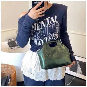 Detail of dark green metallic crossbody bag showing drawstring closure and texture