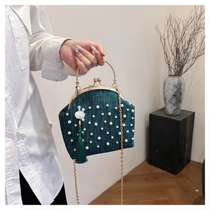 Détail du sac à main en velours vert foncé avec perles et breloque à long pompon élégant