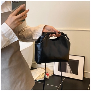 Detail of glossy black leather tote bag with cloud silhouette and fine texture surface