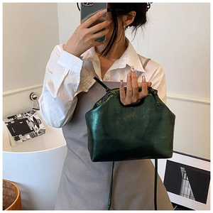 Detailed mirror selfie of a dark green leather handbag with metallic sheen and thin strap