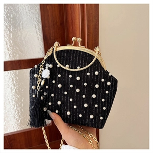 Détail d'un sac de soirée noir orné de perles avec poignée dorée et pompons élégants