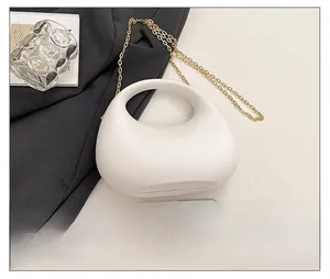 Mini cream pebble-shaped acrylic handbag shown with gold chain next to a smartphone