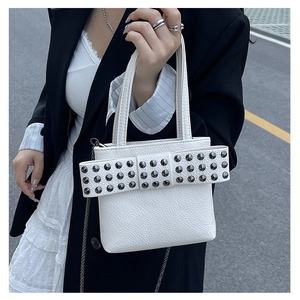 Détail du sac à main blanc texturé litchi avec grand nœud clouté et bandoulière