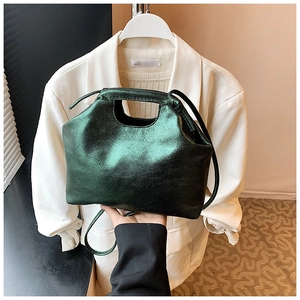Detail of dark green metallic handbag with top handle and adjustable thin shoulder strap