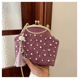 Détail du sac en velours violet avec perles, fermoir doré et pompon fleuri chic