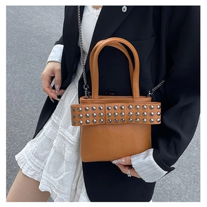Brown leather mini tote bag with rivet bow detail and chain strap on female model