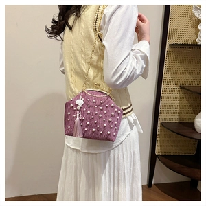 Détail du sac en velours violet avec perles et breloque fleur sur robe blanche