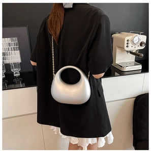 Modern silver crescent moon acrylic clutch bag shown with detachable gold chain strap