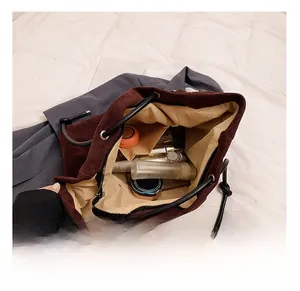 Detail of spacious burgundy suede bucket bag interior holding various cosmetic bottles