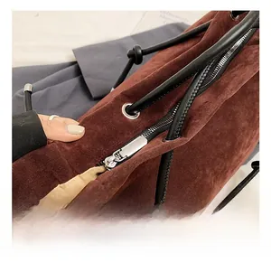 Close-up of matte brown suede tote bag with silver zipper and black leather handles