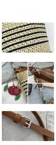 Detail of woven straw bag with cherry charm, zipper closure and adjustable strap buckle