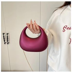 Détail d'un sac à main en acrylique magenta en forme de croissant avec chaîne dorée