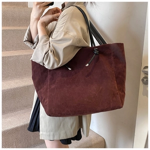Close-up of burgundy frosted tote bag with black strap showing suede texture detail