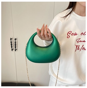 Détail du sac croissant vert émeraude en résine polie avec bandoulière chaîne dorée