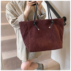Detail of burgundy tote bag with matte texture and black knotted shoulder straps