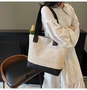 Detail of minimalist woven tote bag with contrast black faux leather base and handles