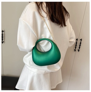 Détail du sac à main en acrylique vert en forme de galet avec chaîne dorée sur mannequin