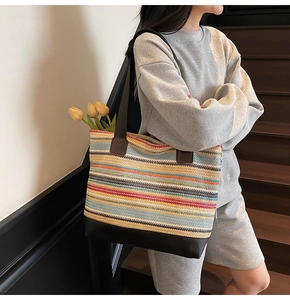 Detail of colorful woven tote bag with brown leather handles and striped bohemian texture
