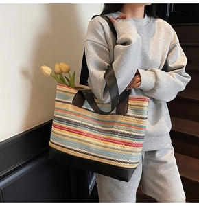 Detail of colorful striped woven tote bag with sturdy black base and double handles