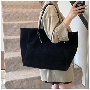 Close-up of a large black matte tote bag featuring minimalist metal ring hardware detail