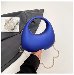 Gros plan d'une pochette de soirée en acrylique bleu roi avec chaîne dorée sur fond chic