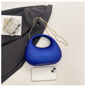 Détail du sac bandoulière demi-lune bleu roi avec chaîne dorée sur surface texturée