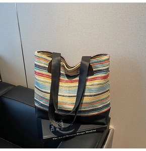 Detail of rainbow striped woven tote bag with reinforced black leather base and straps