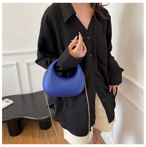 Close-up of royal blue acrylic crescent evening bag with elegant gold chain strap