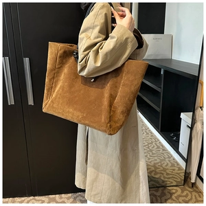 Detail of large brown suede tote bag with knot handle accents shown in daily use