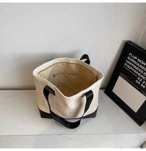 Interior detail of woven tote bag showing beige material and black zipper pocket